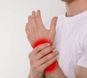 Mann hält schmerzendes Handgelenk – rote Markierung zeigt Rheuma-Schmerzen. Symbolbild für chronische Gelenkschmerzen, die mit Hypnose behandelt werden können.
