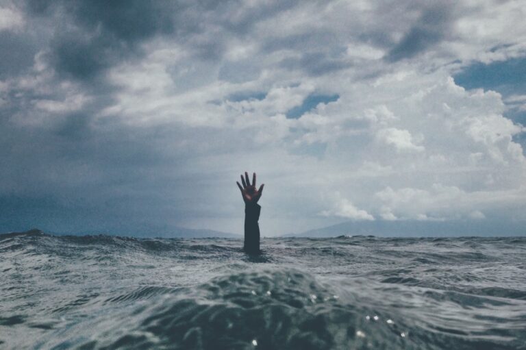 Hand streckt sich aus stuermischem Wasser, Symbolbild fuer Erschoepfung und Burnout
