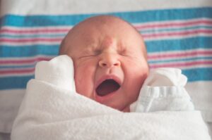 Baby g&auml;hnt eingekuschelt in ein Handtuch, Symbolbild f&uuml;r den 4-Monats-Schlafschub