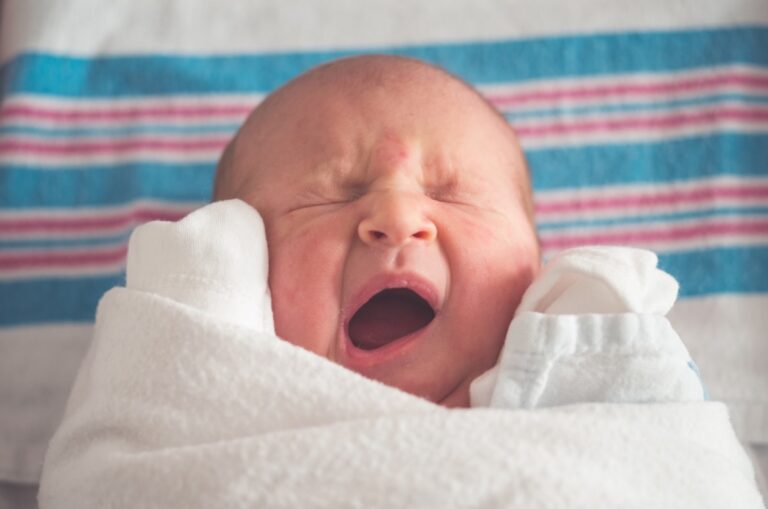 Baby gähnt eingekuschelt in ein Handtuch, Symbolbild für den 4-Monats-Schlafschub