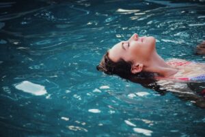 Person entspannt schwimmend im Wasser mit geschlossenen Augen, Symbolbild fuer Vagusnerv-Stimulation und Kaltreiz-Entspannung