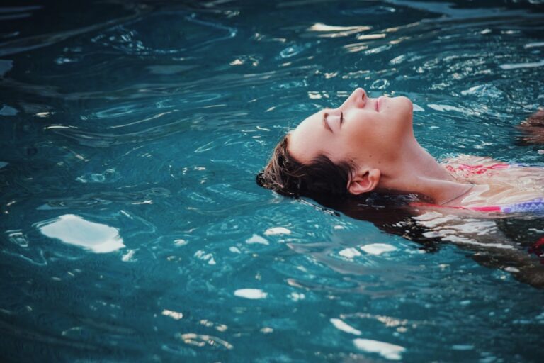 Person entspannt schwimmend im Wasser mit geschlossenen Augen, Symbolbild fuer Vagusnerv-Stimulation und Kaltreiz-Entspannung